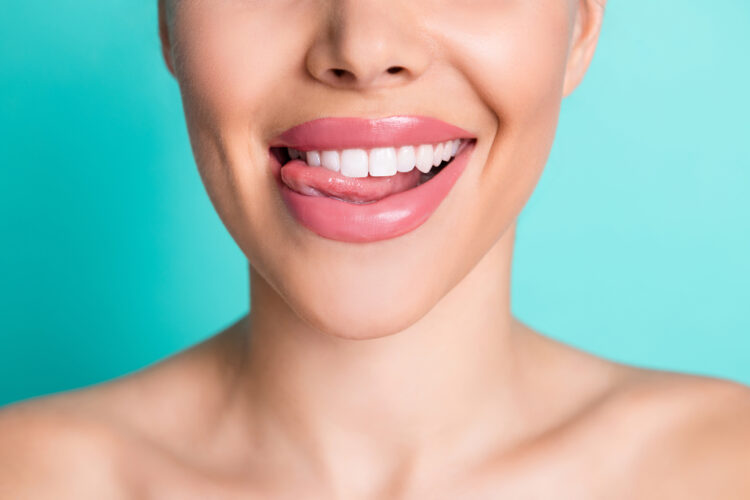 Photo of young cheerful lovely smiling showing tongue and perfect teeth isolated on teal color background.